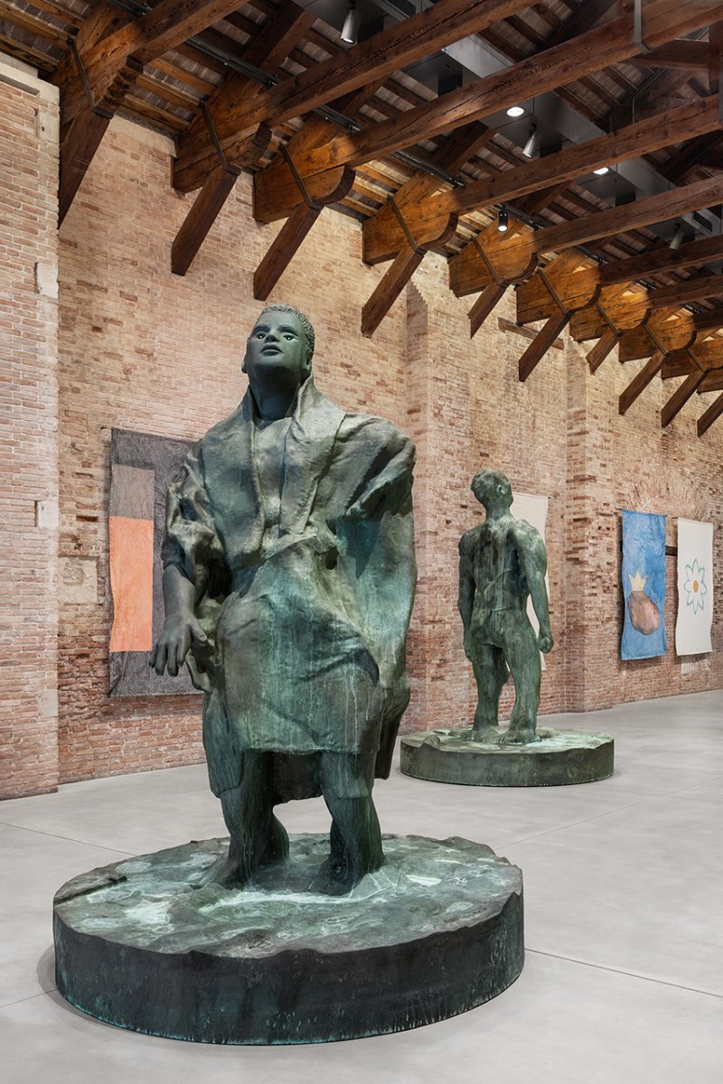Thomas Schütte, "Mann im Wind II", 2018, Pinault Collection; "Mann im Wind I", 2018, Pinault Collection; "DEKA Fahnen", 1989, courtesy the artist and Peter Freeman, Inc., New York/Paris © Thomas Schütte, by SIAE 2025. Installation view, “Thomas Schütte. Genealogies”, 2025, Punta della Dogana, Venezia. Ph. Marco Cappelletti © Palazzo Grassi - Pinault Collection Thomas Schütte - Punta della Dogana
